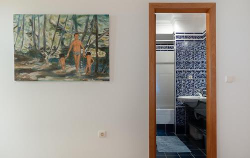 ein Badezimmer mit einem Gemälde einer Familie im Wald in der Unterkunft CASA NA PRAIA in Vila Baleira