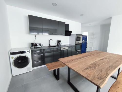 a kitchen with a washing machine and a wooden table at Ferienwohnungen am Stadtgarten Pforzheim in Pforzheim