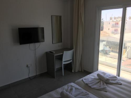 a bedroom with a bed and a desk and a window at Flora Maria Hotel in Ayia Napa