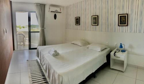 a white bedroom with a large bed and a balcony at Flat na Praia de Intermares in Cabedelo