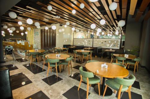 a restaurant with wooden tables and green chairs at Accra Luxury Apartments @ Pearl in Accra