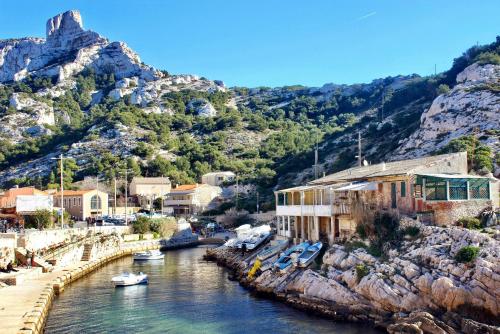 a group of boats in a river with a mountain at Cabanon du Pêcheur, Parc National des Calanques in Marseille