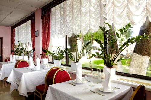 モスクワにあるBusiness Hotel Alekseevskyのダイニングルーム(白いテーブル、椅子、窓付)