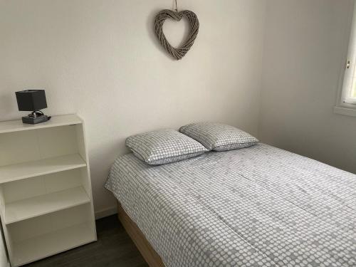 a bedroom with a bed and a heart sign on the wall at Cabourg T2 cosy avec accès direct plage in Cabourg