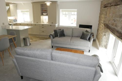 a living room with a couch and a kitchen at Apartment 4 Tomlinsons Apartments in Rothbury