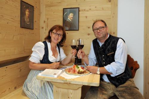 a man and woman sitting at a table with wine glasses at Hotel Goldener Löwe in Kufstein
