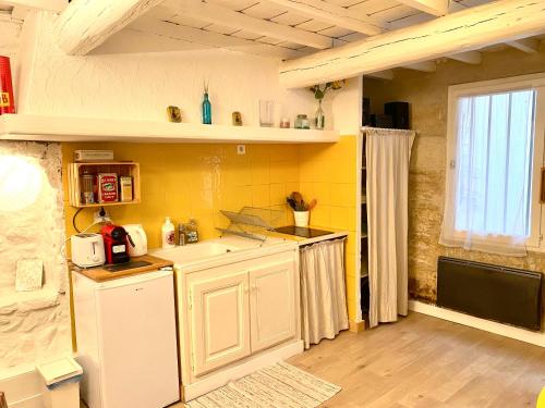 a kitchen with yellow walls and a white refrigerator at La maison de Fanny in Arles