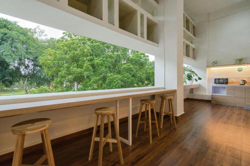 a bar with stools in a kitchen with a large window at Bobopod Alun-Alun, Malang in Bunul