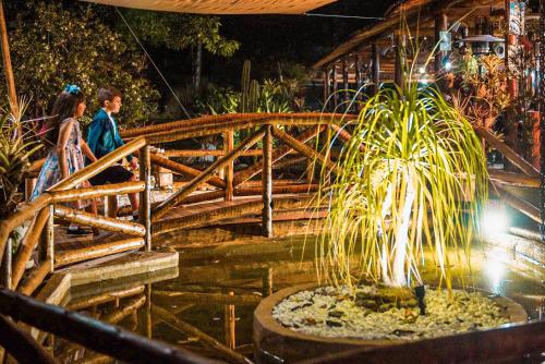 a man and woman walking over a wooden bridge with a fountain at Minha Glória Hotel Boutique in Bom Jardim
