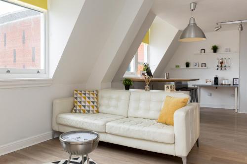 a living room with a white couch and a kitchen at Indigo Apartment in Birmingham
