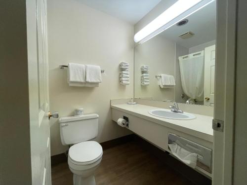 a bathroom with a toilet and a sink and a mirror at Travelodge by Wyndham Fort St John in Fort Saint John