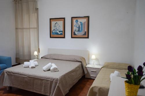 a bedroom with two beds and two pictures on the wall at Ohana by Casimiro in Trapani