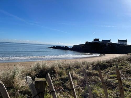 a beach with a fence next to the ocean at No2 at Rosebank Apartments in Moville
