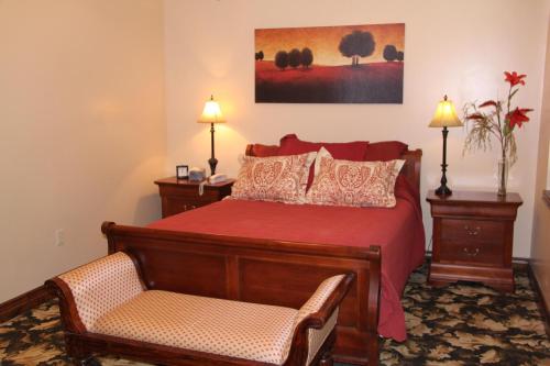 - une chambre avec un lit rouge et une chaise dans l'établissement Caldwell Messenger Suites, à Caldwell