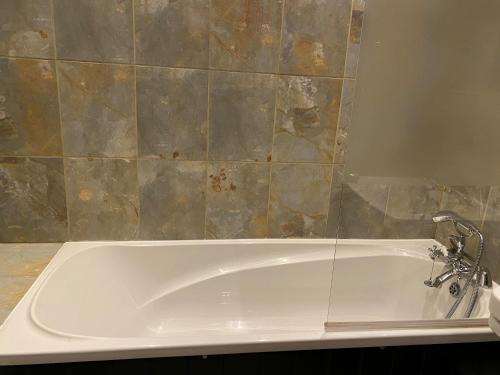 a white bath tub in a bathroom with a tile wall at The Seven Stars in Timsbury