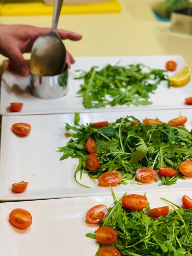 a person is preparing tomatoes and greens on white plates at Alpenpension Gasthof in Ratten