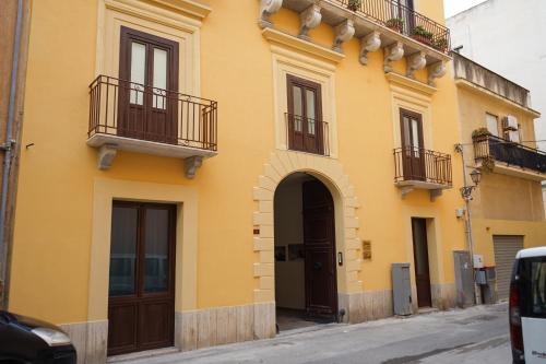 a yellow building with doors and balconies on a street at Ohana by Casimiro in Trapani
