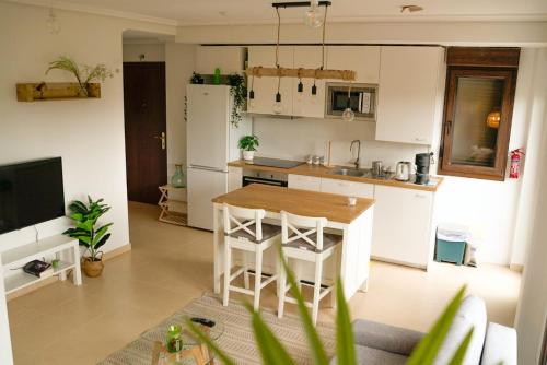 a kitchen with white cabinets and a wooden table at APARTAMENTO con Jardín en Bádames in Bádames