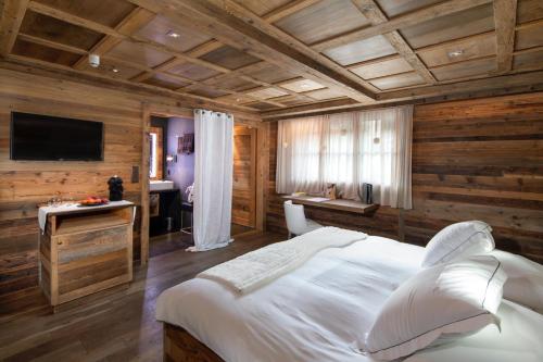 a bedroom with a large white bed and a desk at Hostellerie du Pas de l'Ours "Relais et Châteaux" in Crans-Montana