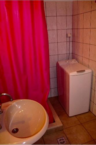 a bathroom with a red shower curtain and a toilet at Dina’s house in Argostoli