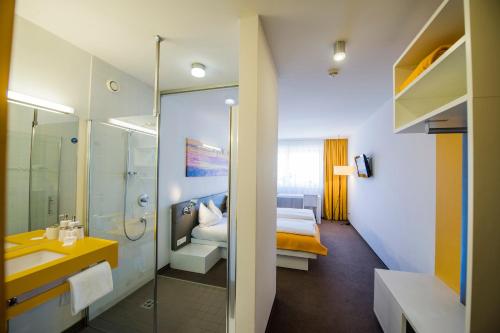 a bathroom with a sink and a bed in a room at STAY.inn Comfort Art Hotel Schwaz in Schwaz