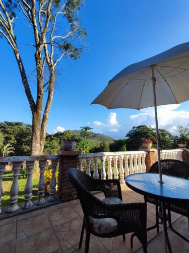 a table and chairs with an umbrella on a balcony at Quinta da Bela Vista in Caeté