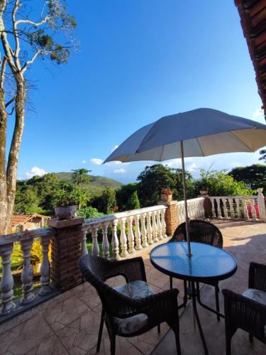 a table and chairs with an umbrella on a balcony at Quinta da Bela Vista in Caeté