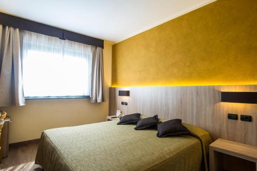 a bedroom with a bed with a yellow wall and a window at Sangallo Park Hotel in Siena