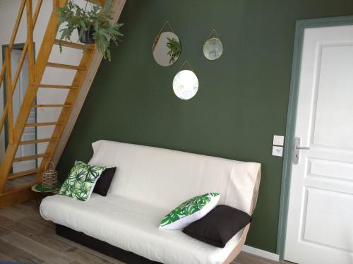 un sofá blanco en una sala de estar con paredes verdes en Les petits gites, en Ernée