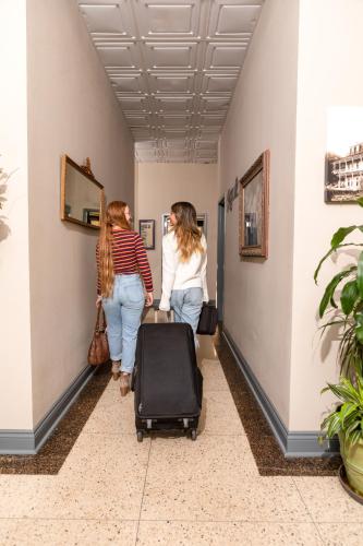 two women walking down a hallway with a suitcase at The Bank Hotel in Lake Arthur