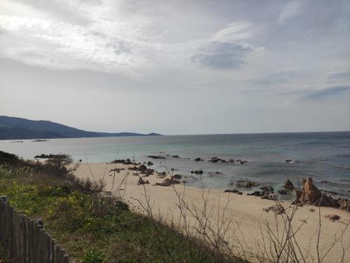 a beach with rocks in the water and a fence at A Casa Vadiiolina - Chambres d'hôtes d'exception in Sollacaro