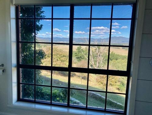 a window with a view of a lake and mountains at Rosewhite House in Myrtleford