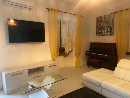 sala de estar con sofá blanco y piano en white appartament, en Bagnolo Piemonte