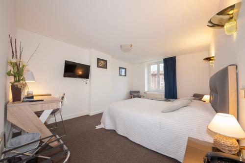 a bedroom with a bed and a desk and a television at Relais Lorraine Alsace Pere & Fils in Raon-lʼÉtape