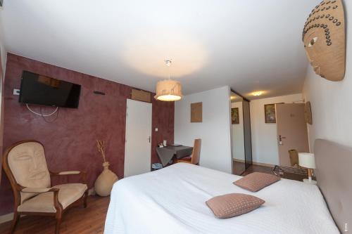 a bedroom with a bed and a chair and a tv at Relais Lorraine Alsace Pere & Fils in Raon-lʼÉtape