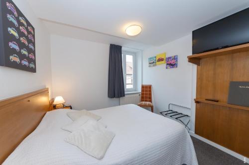 a bedroom with a white bed and a flat screen tv at Relais Lorraine Alsace Pere & Fils in Raon-lʼÉtape