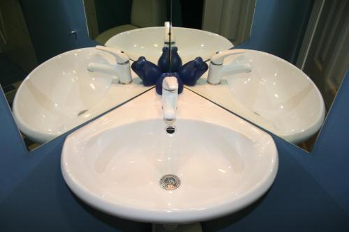 a white sink with a blue bow in front of a mirror at Matrix Garden Apartments in Tallinn
