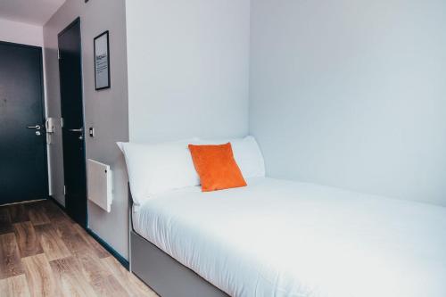 an orange pillow on a white bed in a room at Quarter by the Warren Collection in Belfast