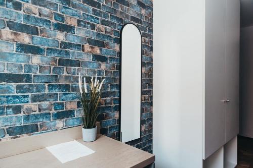 a brick wall with a table with a plant on it at Quarter by the Warren Collection in Belfast