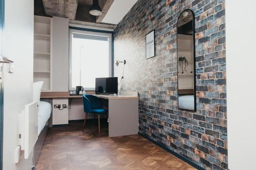 an office with a brick wall and a desk with a computer at Quarter by the Warren Collection in Belfast