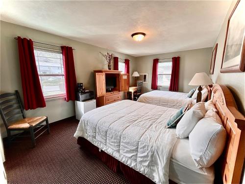 a bedroom with two beds with red curtains at Rugged Country Lodge in Pendleton