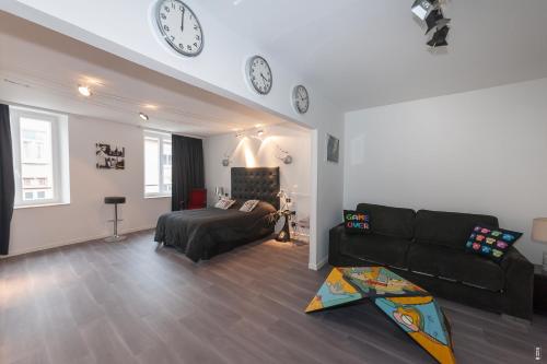 a living room with a couch and clocks on the wall at Relais Lorraine Alsace Pere & Fils in Raon-lʼÉtape