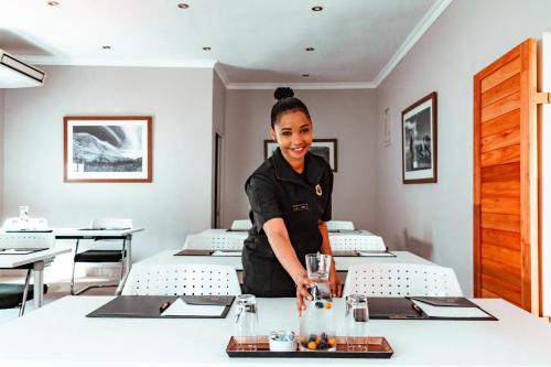 a woman standing behind a table in a restaurant at Tulbagh Boutique Heritage Hotel in Tulbagh