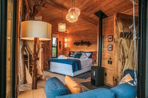 1 dormitorio en una cabaña de madera con 1 cama y 1 sofá en Casa na Árvore Morada dos Vagalumes, en Farroupilha