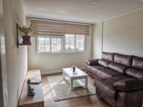 a living room with a brown couch and a table at APTO. SANXURXO in Camariñas