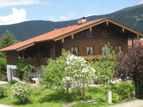 een groot houten huis met bergen op de achtergrond bij Ferienwohnung Gundi Scheurl - Chiemgau Karte in Inzell
