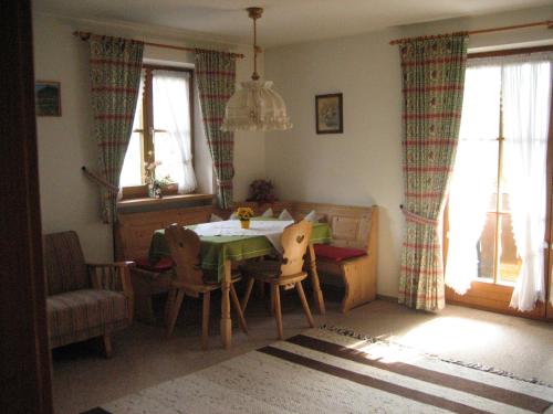 een eetkamer met een tafel, stoelen en ramen bij Ferienwohnung Gundi Scheurl - Chiemgau Karte in Inzell