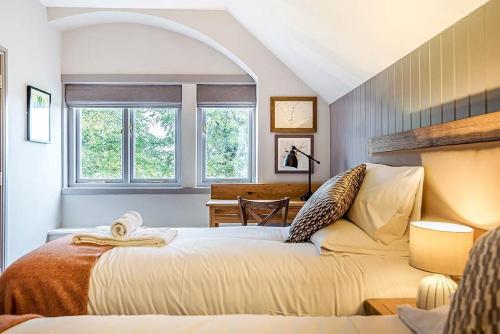 a bedroom with a bed and a desk and two windows at Charlcombe Inn in Bath