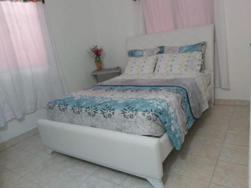 1 dormitorio con cama blanca y edredón azul en Casa ITCI Tours en Cartagena de Indias