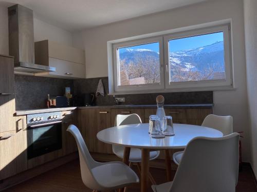 eine Küche mit einem Tisch mit Stühlen und einem Fenster in der Unterkunft Alpenlodge Pitztal in Wenns